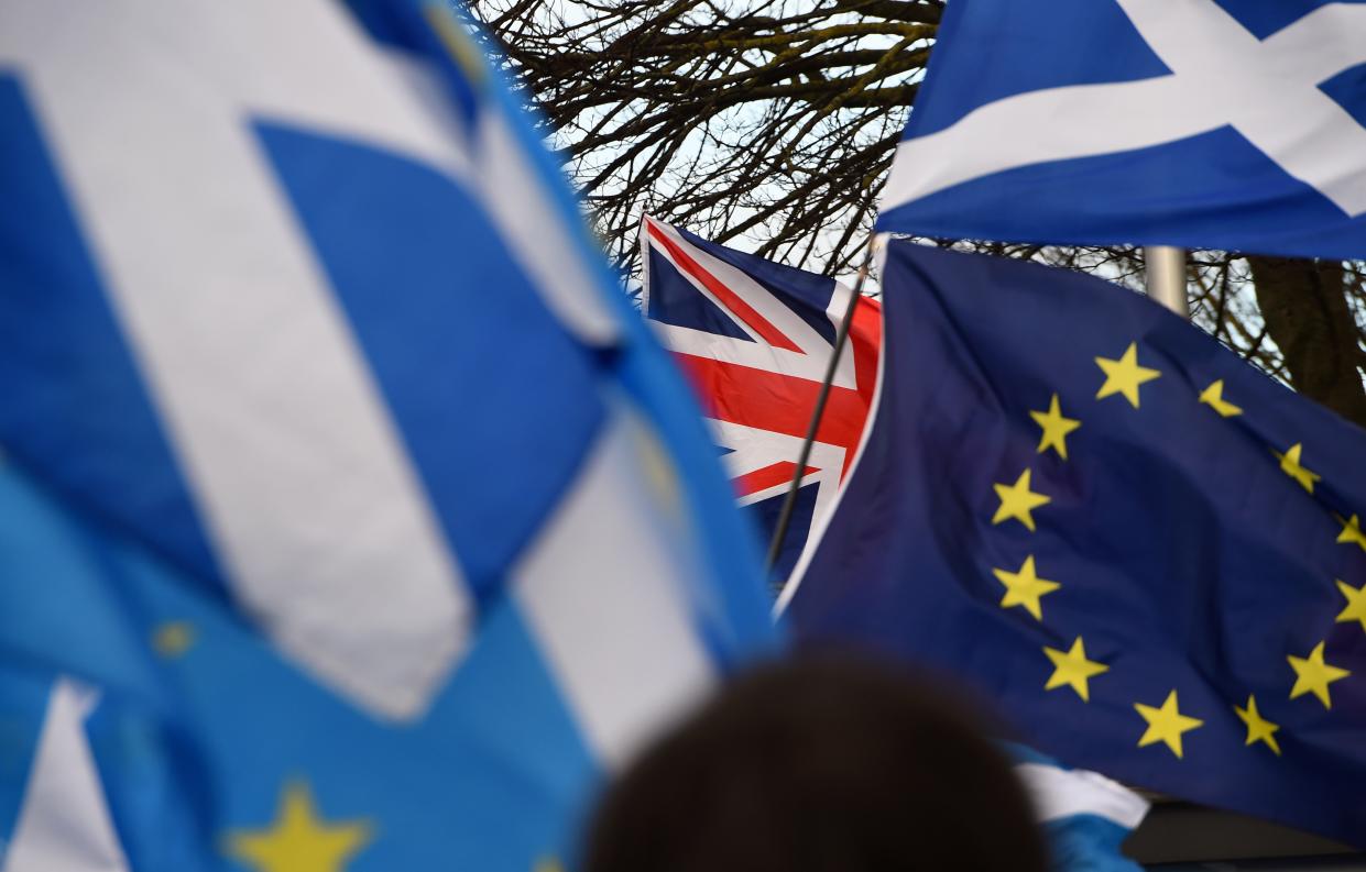 Pro-Union activists wave a Union flag (C) as Scottish Saltire and EU flags fly during an anti-Conservative government, pro-Scottish independence, and anti-Brexit demonstration outside Holyrood, the seat of the Scottish Parliament in Edinburgh on February 1, 2020. - Britain began its post-Brexit uncertain future outside the European Union on Saturday after the country greeted the historic end to almost half a century of EU membership with a mixture of joy and sadness. There were celebrations and tears on Friday as the EU's often reluctant member became the first to leave an organisation set up to forge unity among nations after the horrors of World War II. (Photo by ANDY BUCHANAN / AFP) (Photo by ANDY BUCHANAN/AFP via Getty Images)