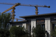 Construction cranes stand near an Evergrande new housing development showroom office building in Beijing, Wednesday, Sept. 22, 2021. The Chinese real estate developer whose struggle to avoid defaulting on billions of dollars of debt has rattled global markets announced Wednesday it will make a closely watched interest payment due this week, while the government was silent on whether it might intervene. (AP Photo/Andy Wong)