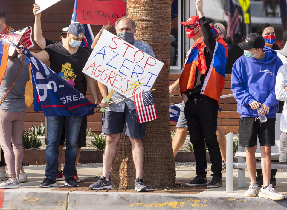 Pro Trump supporters and protesters against the escalating conflict between Armenia and neighboring Azerbaijan hold signs and flags along President Trump's motorcade route to a fundraiser in Newport Beach, Calif., Sunday, Oct. 18, 2020. (Leorard Ortiz/The Orange County Register via AP)