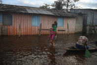 A mother carries her daughter to school on a street flooded by the rise of the Negro river in Iranduba, Amazonas state, Brazil, Monday, May 23, 2022. The Amazon region is being hit hard by flooding with 35 municipalities that are facing one of their worst floods in years and the water level is expected to rise over the coming months. (AP Photo/Edmar Barros)