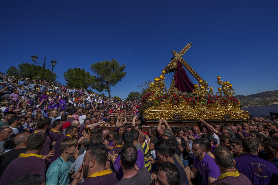 Penitents of the "Padre Jesus Nazareno" brotherhood carry a portable dais platform which supports a statue of Jesus Christ carried by "costaleros"during the holy week procession in Priego de Cordoba, southern Spain, Friday, April 7, 2023. Hundreds of processions take place throughout Spain during the Easter Holy Week. (AP Photo/Manu Fernandez)