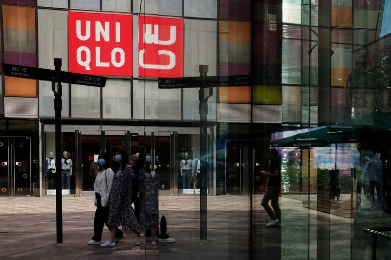 FILE PHOTO: Women walk past a store of the Fast Retailing's fashion chain Uniqlo, in Beijing