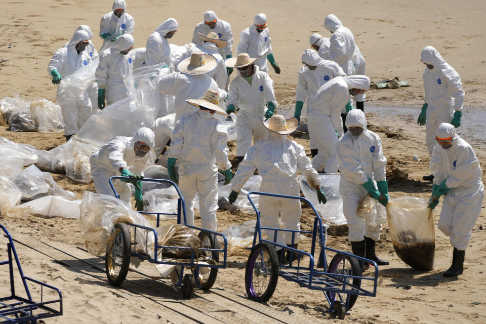 Workers carry out a cleanup operation on Mae Ramphueng Beach after a pipeline oil spill off the coast of Rayong province in eastern Thailand, Sunday, Jan. 30, 2022. The governor of a province in eastern Thailand on Saturday declared a state of emergency after an oil slick washed up on a sand beach, shutting down restaurants and shops in a setback for the pandemic-hit tourism industry. (AP Photo/Sakchai Lalit)