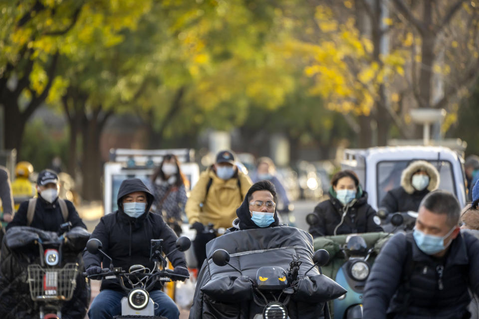 Commuters wearing face masks ride along a street in Beijing, Wednesday, Nov. 16, 2022. Chinese authorities locked down a major university in Beijing on Wednesday after finding one COVID-19 case as they stick to a "zero-COVID" approach despite growing public discontent. (AP Photo/Mark Schiefelbein)