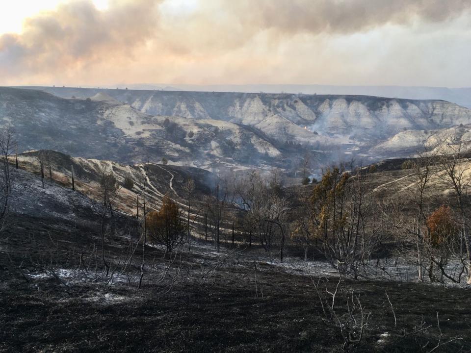 A wildfire smolders near the Burning Hills Amphitheatre Thursday, April 1, 2021 near Medora, N.D. Officials say firefighters have stopped a wildfire from spreading in the western North Dakota tourist town of Medora, where its 100 residents were forced to evacuate. (Tom Stromme/The Bismarck Tribune via AP)