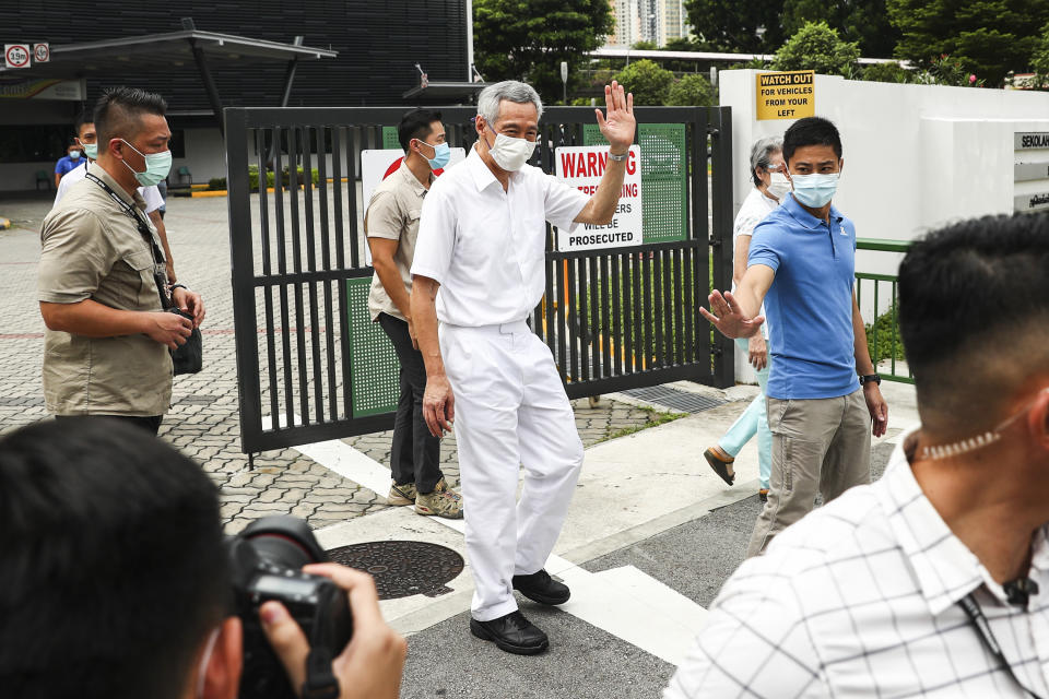 People's Action Party Secretary-General and Singaporean Prime Minister Lee Hsien Loong, center, wearing a mask, waves as he departs the Alexandra Primary School polling center after casting his vote in Singapore, Friday, July 10, 2020. Wearing masks and plastic gloves, Singaporeans began voting in a general election that is expected to return Prime Minister Lee's long-governing party to power. (AP Photo)