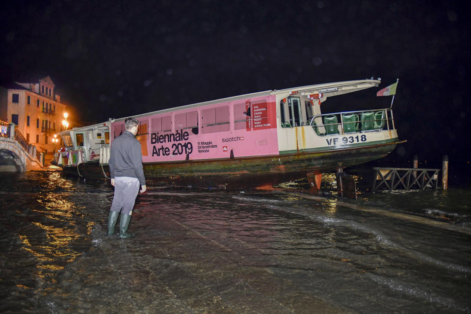 A man looks at a stranded ferry boat, in Venice, Italy, early Wednesday, Nov. 13, 2019. The mayor of Venice is blaming climate change for flooding in the historic canal city that has reached the second-highest levels ever recorded, as another exceptional water level was recorded Wednesday. (AP Photo/Luigi Costantini)