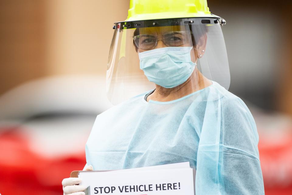 A Heath care worker stands on Buford Street to direct them to the Corpus Christi drive-thru COVID-19 testing center at the old CHRISTUS Spohn Memorial Hospital parking lot on Thursday March 19, 2020.