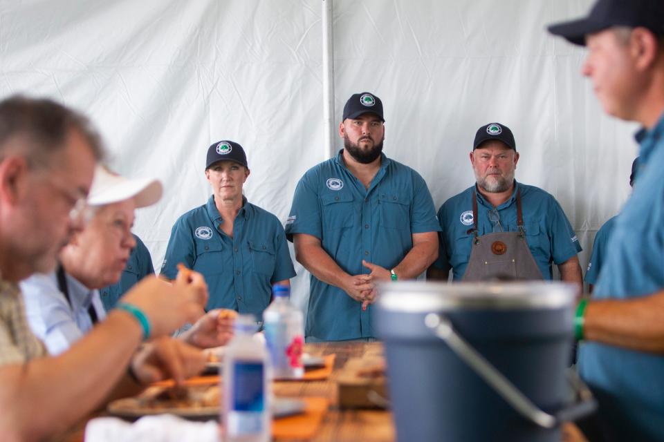 Dustey Walley, right, with Hometown BBQ speaks with two judges as they eat pieces of the team’s whole hog entry as fellow team members Holly Jubera, Dustin Stanford and Noel Grafe look on during the Memphis in May World Championship Barbecue Cooking Contest on May 18, 2024, at Liberty Park in Memphis. “We get to picking on him calling him team leader,” Grafe joked about Walley. “But at the end of the day, we all know we win as a team and lose as a team.”