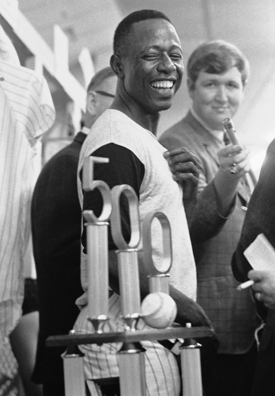 FILE- In this July 14, 1968, file photo, Atlanta Braves' Hank Aaron smiles as he looks at the trophy presented him by Braves President Bill Bartholomay, after Aaron hit his 500th career home run in Atlanta. Hank Aaron, who endured racist threats with stoic dignity during his pursuit of Babe Ruth but went on to break the career home run record in the pre-steroids era, died early Friday, Jan. 22, 2021. He was 86. The Atlanta Braves said Aaron died peacefully in his sleep. No cause of death was given. (AP Photo/Charles Kelly, File)