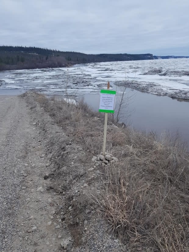 This sign, on the point where Jackfish Creek meets the Mackenzie River, marks the trigger point for the community of Fort Good Hope, N.W.T. 'If water reaches this point, a STATE OF EMERGENCY will be activated and Evacuation Warnings will be issued,' the sign reads.  (Submitted by Roger Plouffe - image credit)