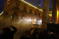 Anti-government protesters are sprayed by a water cannon as they clash with the riot police during ongoing protests in Beirut, Lebanon, Wednesday, Jan. 22, 2020. Lebanon's new government has held its first meeting a day after it was formed following a three-month political vacuum. (AP Photo/Bilal Hussein)