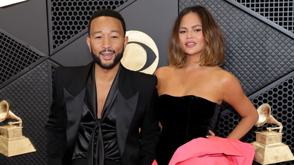 John Legend wore a black tuxedo with silken blouse, while his wife and TV personality Chrissy Teigan opted for a short black velvet Alexandre Vauthier Couture dress with a bouffant rose-shaped hemline. - Kayla Oaddams/WireImage/Getty Images