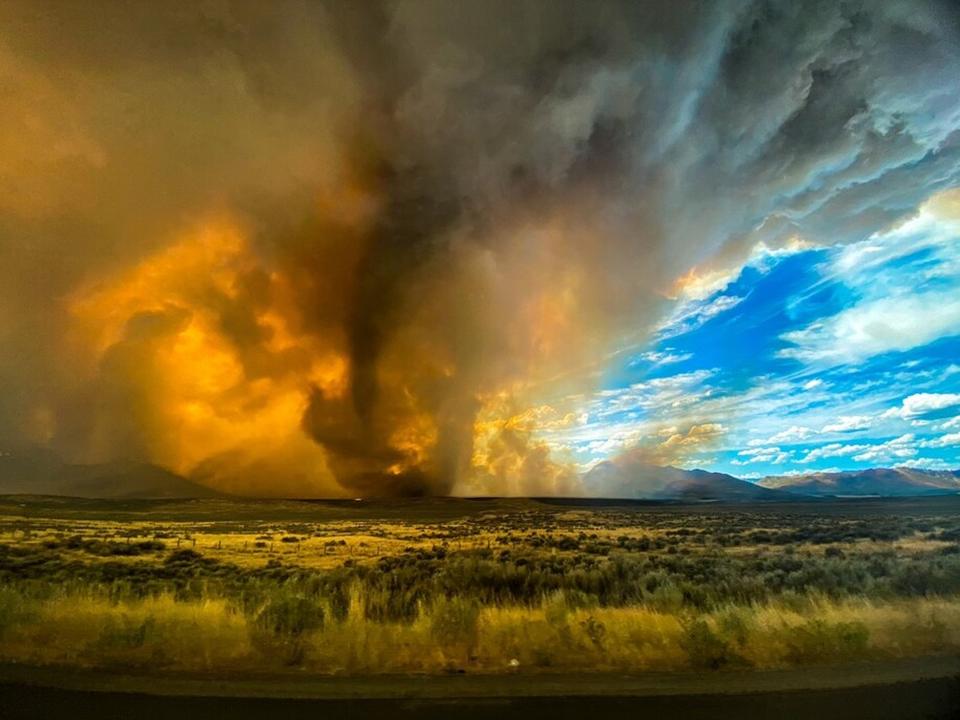 This photo provided by Katelynn & Jordan Hewlett, a funnel appears in a thick plume of smoke from the Loyalton Fire is seen in Lassen County, Calif., Saturday, Aug. 15, 2020. A wildfire in Northern California on Saturday spawned at least one fire tornado that prompted the National Weather Service to issue a tornado warning. The Loyalton Fire in Lassen County, Calif., burned intensely amid hot and dry conditions on Saturday afternoon. (Katelynn & Jordan Hewlett via AP)