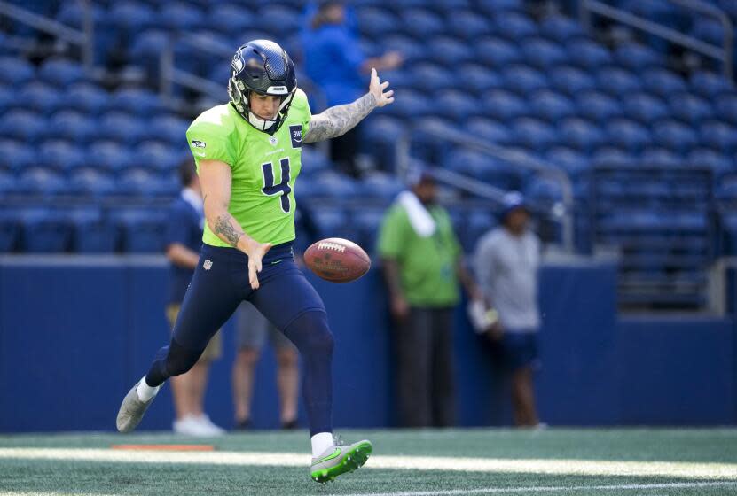 The Seahawks' Michael Dickson drops the ball, extends his arms and prepares to punt the football during warmups