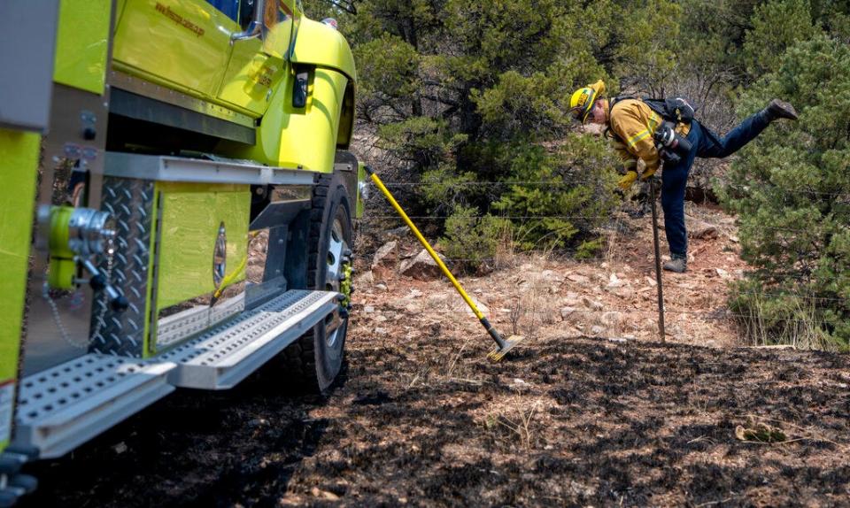 Jeff Franco, a wildland firefighter from Apple Valley, Calif., crosses a barbed wire fence after mopping up hot spots along NM 283 near Las Vegas, N.M., Thursday, May 5, 2022. Firefighters are trying to hold the Calf Canyon/Hermit Peak Fire at the road and not let it cross.