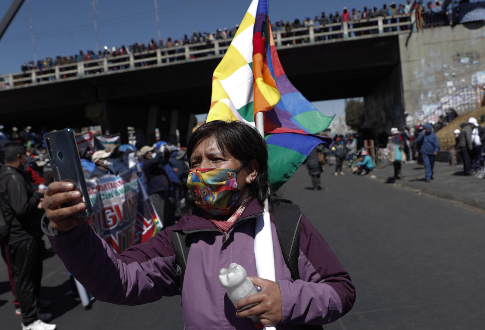 Una mujer con una máscara para protegerse del COVID-19 toma una foto con su teléfono celular durante una protesta contra el aplazamiento de las elecciones presidenciales en El Alto, Bolivia, el jueves 13 de agosto de 2020. (AP Foto/Juan Karita)