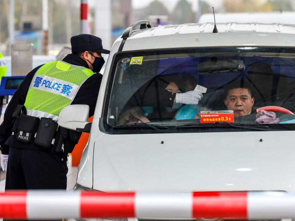 A policeman uses a digital thermometer to take a driver's temperature at a checkpoint at a highway toll gate in Wuhan in central China's Hubei Province, Thursday, Jan. 23, 2020. China closed off a city of more than 11 million people Thursday in an unprecedented effort to try to contain a deadly new viral illness that has sickened hundreds and spread to other cities and countries amid the Lunar New Year travel rush. (Chinatopix via AP)