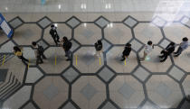 Visitors wearing face masks as a precaution against the coronavirus, wait in a line while maintaining social distancing outside of an exhibition hall in Seoul, South Korea, Wednesday, Oct. 21, 2020. (AP Photo/Lee Jin-man)