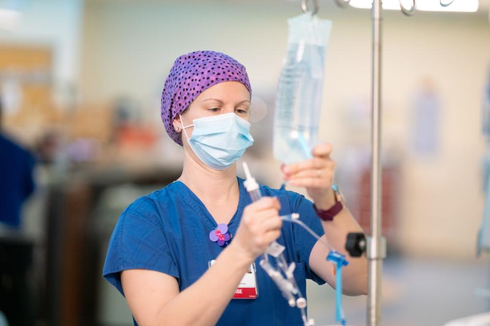 Catharine Krause, a registered nurse with UW Health in Madison, checks fluids coming from an IV bag.