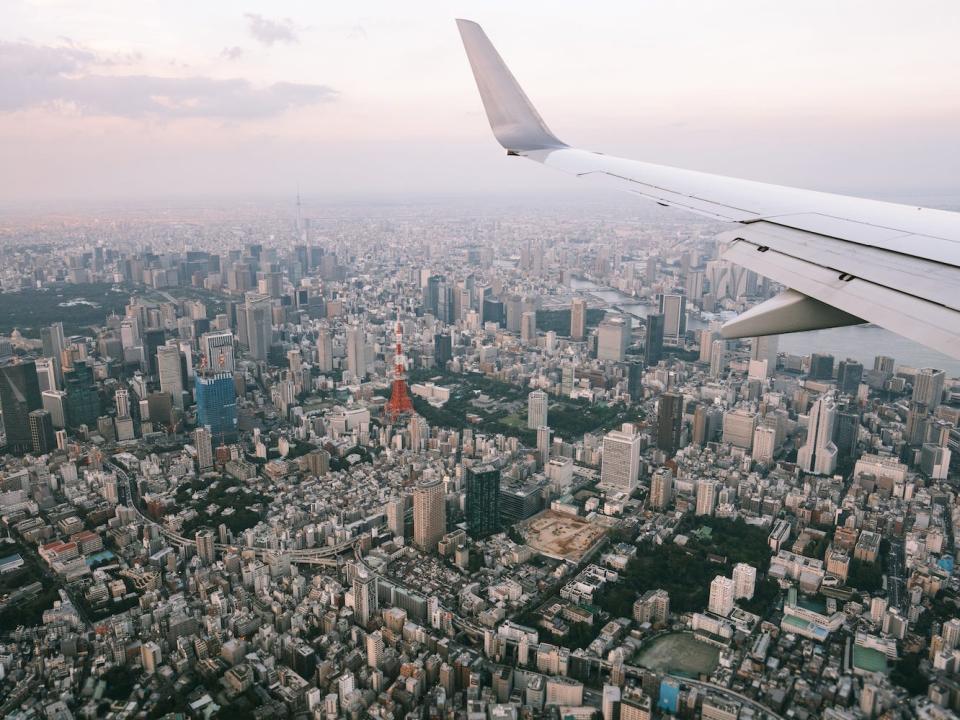 Aerial view of Tokyo from airplane window with the plane wing visible over the city.