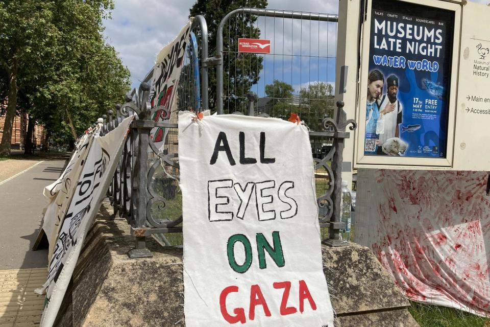 Placards on fences outside encampment, including 'All Eyes on Gaza"