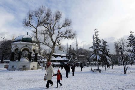 Tourists stroll on the snow-covered Sultanahmet Square in the historic old town of Istanbul February 18, 2015. REUTERS/Murad Sezer