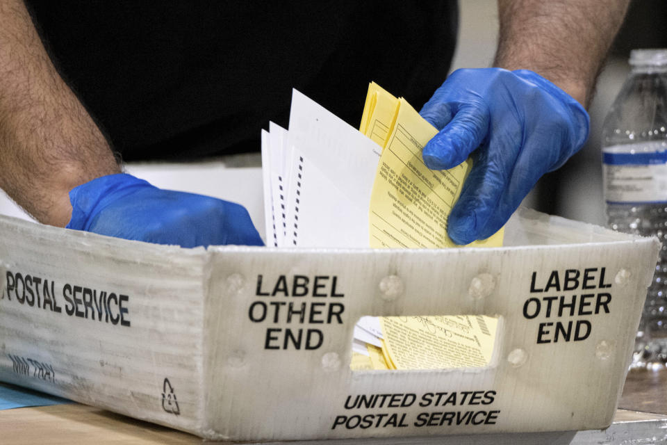 FILE - In this Jan. 5, 2021 file photo, Fulton County Georgia elections workers process absentee ballots for the Senate runoff election in Atlanta. When voters in Florida and Georgia request mailed ballots next year, they will have to make sure they do one more thing before sending it in: provide proof of identification. (AP Photo/Ben Gray, File)