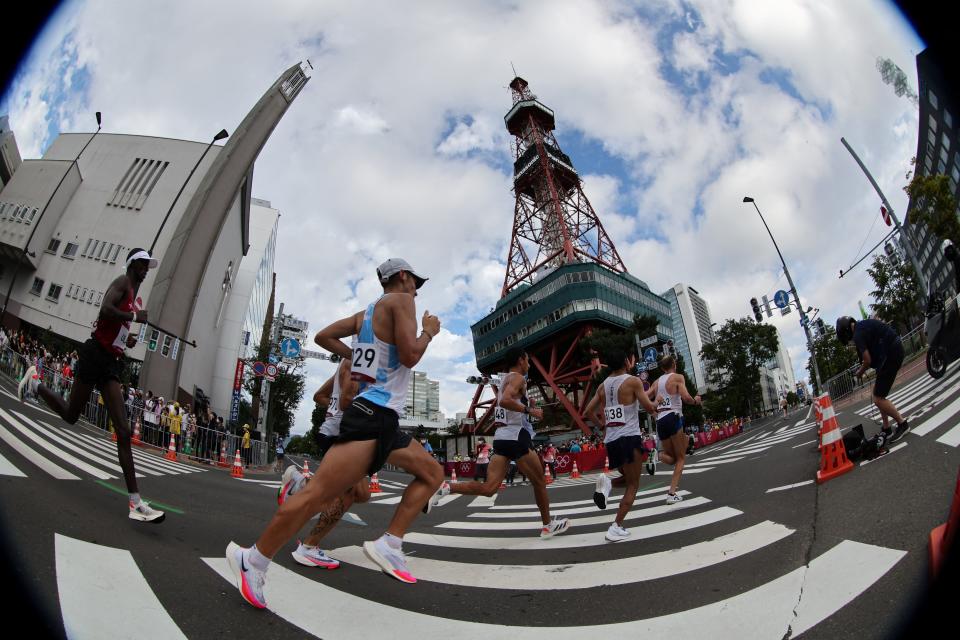 <p>A fish eye lens shows athletes passing under the Sapporo TV Tower as they compete the men's marathon final during the Tokyo 2020 Olympic Games in Sapporo on August 8, 2021. (Photo by Giuseppe CACACE / AFP)</p> 