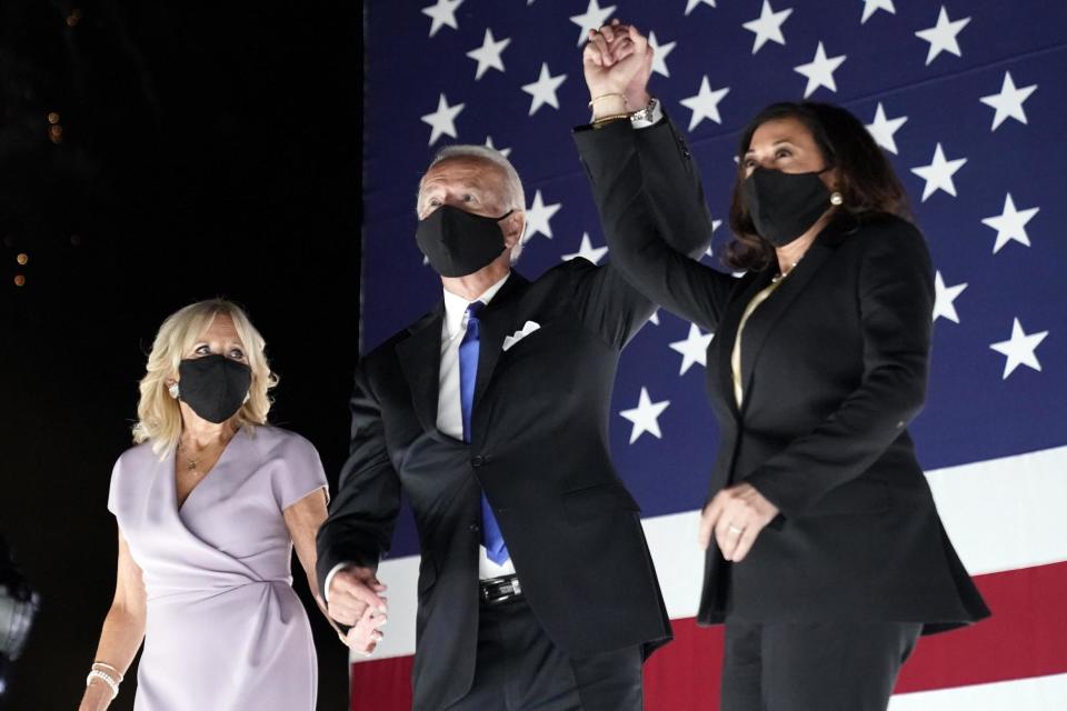 Joe Biden and Kamala Harris hold hands as fireworks explode behind them (AP)