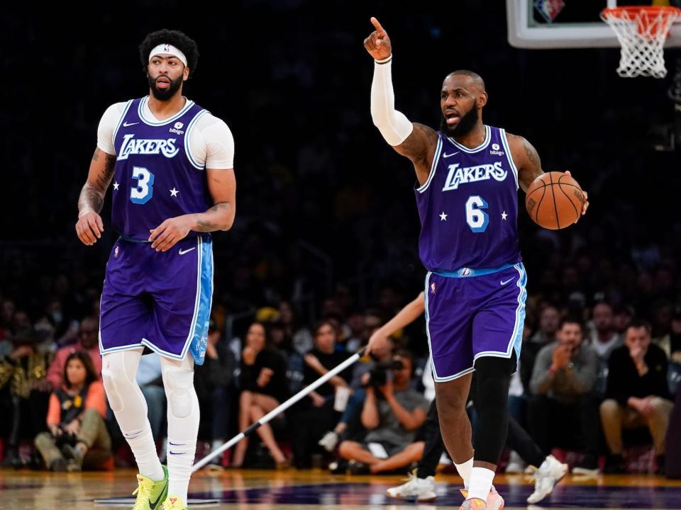 Anthony Davis runs up the court while LeBron James dribbles the ball and points during a Lakers game.