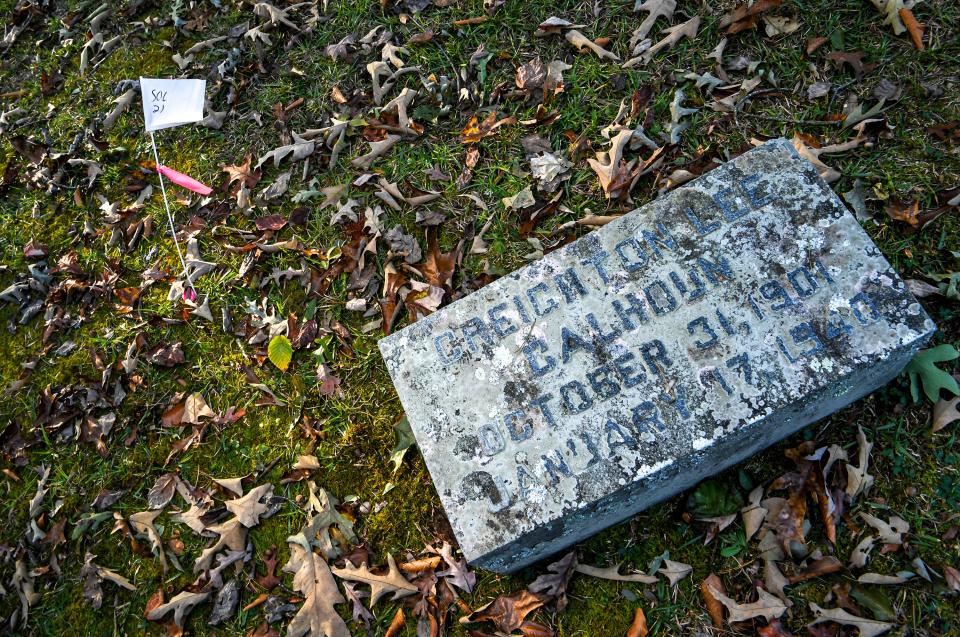 A white flag "SOL 21" is next to the gravestone of Creighton Lee Calhoun (1901-1940) in the gated plot Calhoun Plantation Cemetery, at Woodland Cemetery in Clemson.