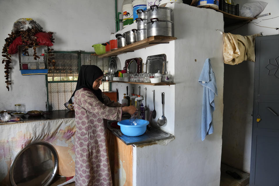 A woman washes dishes in a bowl to save water at Harf Beit Hasna village, in Dinnieh province, north Lebanon, Wednesday, Sept. 7, 2022. Farmers in a small mountainous town in Lebanon's northern Dinnieh province once could rely on rain to irrigate their crops and sustain a living. But climate change and the country's crippling economic crisis has left their soil dry and their produce left to rot. They rely on the little rain they can collect in their artificial ponds to make enough money to feed themselves, as they live without government electricity, water, and services. ( AP Photo/Hussein Malla)