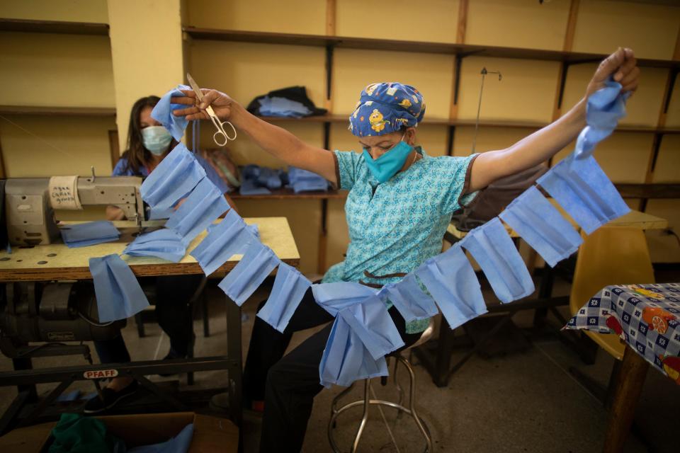 A worker of the state-owned Concepcion Palacios Maternity Hospital manufactures face masks in Caracas, Venezuela, March 17, 2020. Workers of the city's main maternity are preparing makeshift masks with disposable blue sheets to distribute to medical staff and other workers of the health center for protection of an eventual spread of the COVID-19 illness.