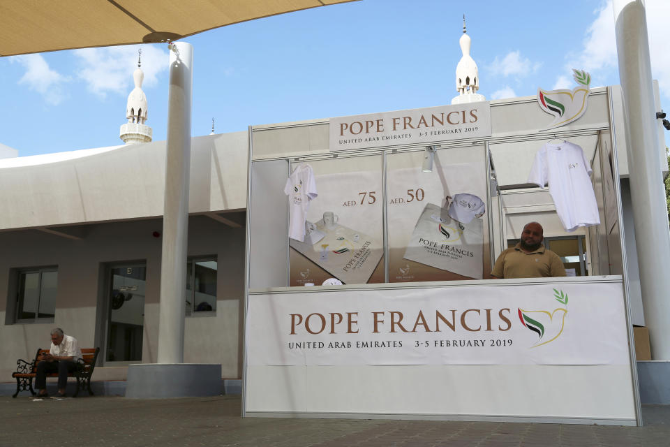In this Sunday, Jan. 20, 2019 photo, a man sells memorabilia for Pope Francis' upcoming trip to the United Arab Emirates at St. Mary's Catholic Church in Dubai, United Arab Emirates. The minarets of a mosque can be seen behind his stand. The Catholic Church's parishioners in the UAE come from around the world and will offer an international welcome to Pope Francis on his visit Feb. 3 through Feb. 5. It is the first papal visit in history to the Arabian Peninsula, the birthplace of Islam. (AP Photo/Jon Gambrell)
