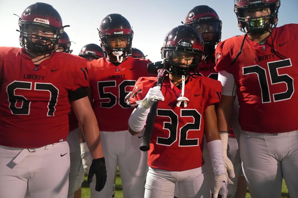 Liberty's Owen  Dalton (32) carries a sledge hammer as he takes the field with his teammates before they play Pinnacle at Liberty High School in Peoria on Saturday, Sept. 10, 2022.