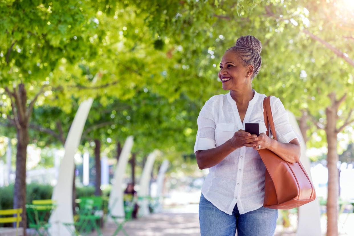 Senior woman walking outside with her phone