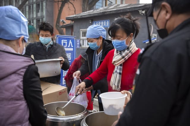 Workers in face masks dispense lunch outside of an office building in Beijing