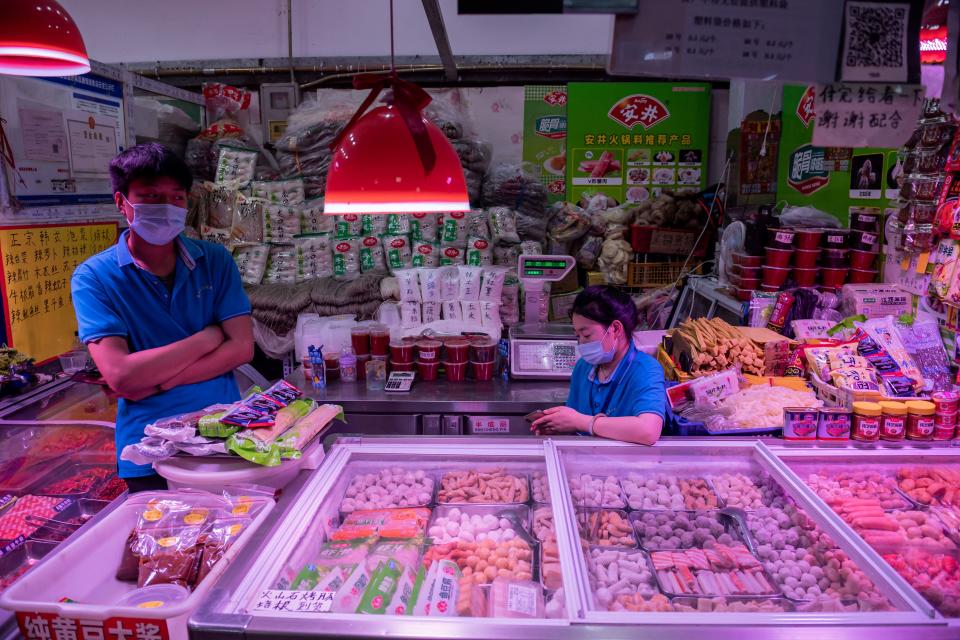 Vendors wait for customers at their stall selling frozen meat and seafood balls at a market in Beijing on June 20, 2020. - Tens of thousands of people in the Chinese capital are being tested for the COVID-19 coronavirus while neighbourhoods have been locked down and schools closed as authorities seek to contain a cluster linked to the Xinfadi food market. (Photo by NICOLAS ASFOURI / AFP) (Photo by NICOLAS ASFOURI/AFP via Getty Images)