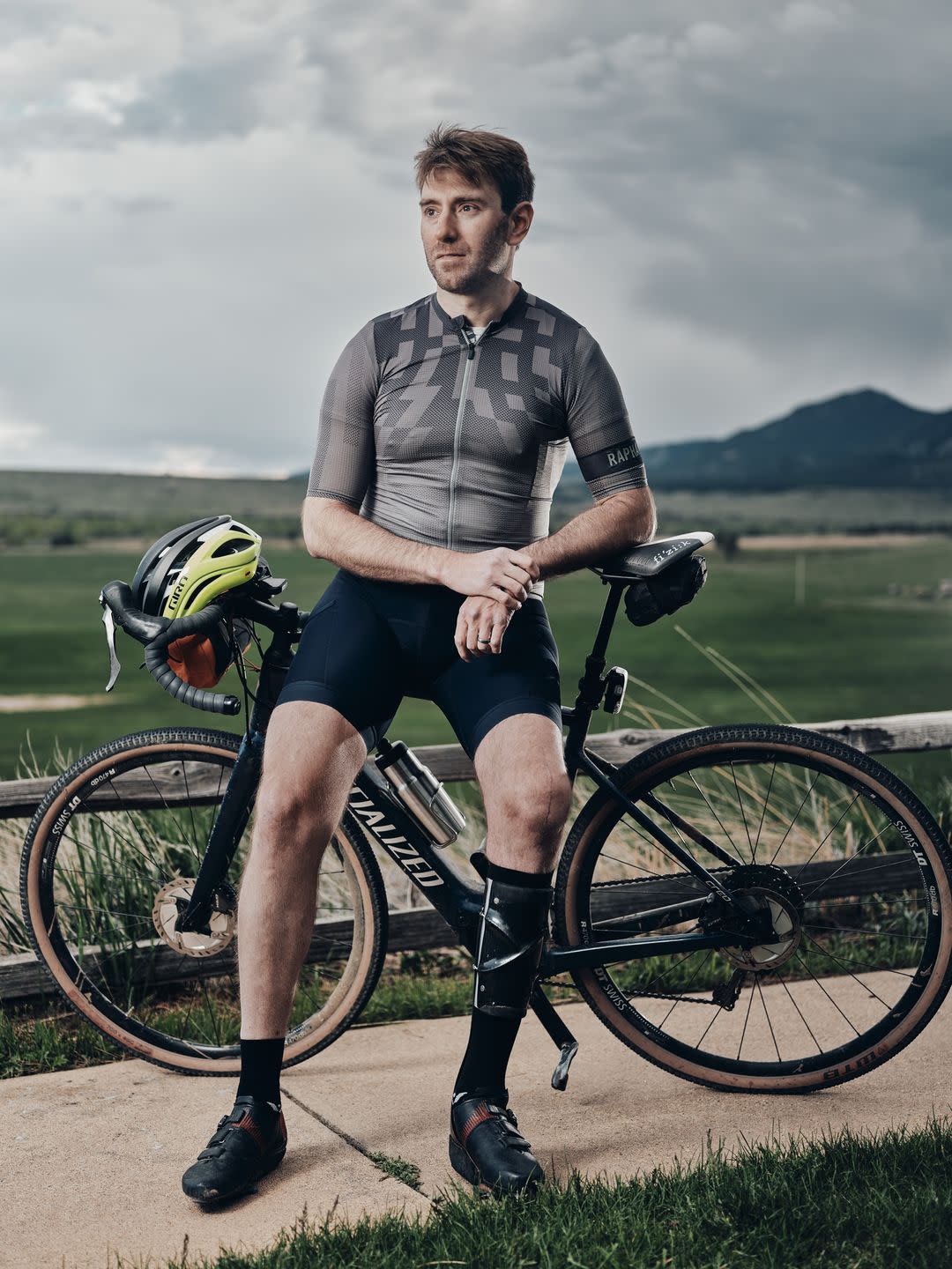 a man wearing cycling gear and a leg brace poses for a portrait