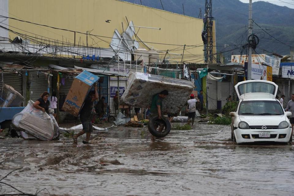 People carry away a mattress, a television monitor and a bicycle from a store at a shopping mall after Hurricane Otis ripped through Acapulco in 2023.