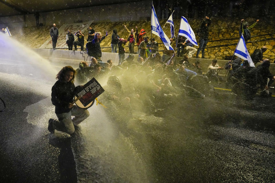 Police use a water cannon to disperse demonstrators protesting against Israeli Prime Minister Benjamin Netanyahu's government, and calling for the release of hostages held in the Gaza Strip by the Hamas militant group, in Tel Aviv, Israel, Saturday, March 9, 2024. With each passing day, the relatives of hostages in Gaza face a deepening despair. (AP Photo/Ariel Schalit)