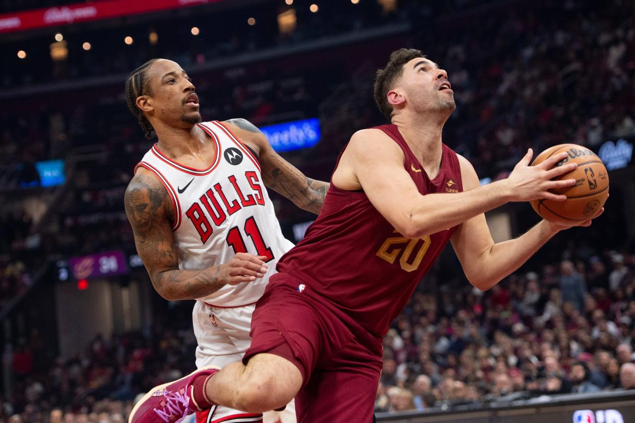Cleveland Cavaliers' Georges Niang (20) drives to the basket past Chicago Bulls' DeMar DeRozan (11) during the first half of an NBA basketball game in Cleveland, Wednesday, Feb. 14, 2024. (AP Photo/Phil Long)