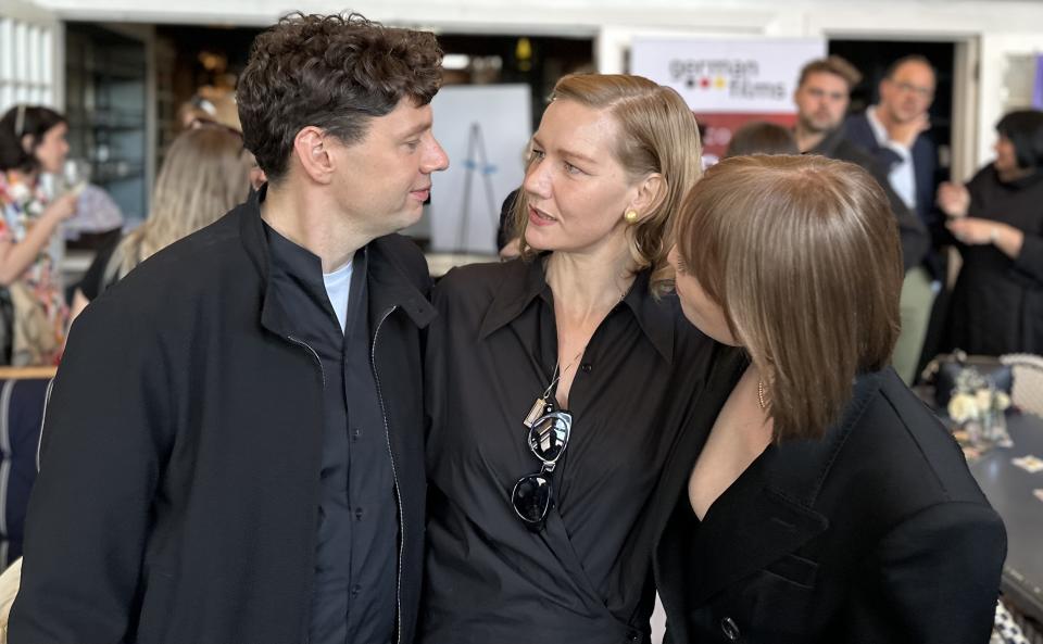 Christian Friedel, Sandra Hüller, Leonie Benesch confer at the German Films Oscar reception. Photo :Baz Bamigboye/<em>Deadline</em>.
