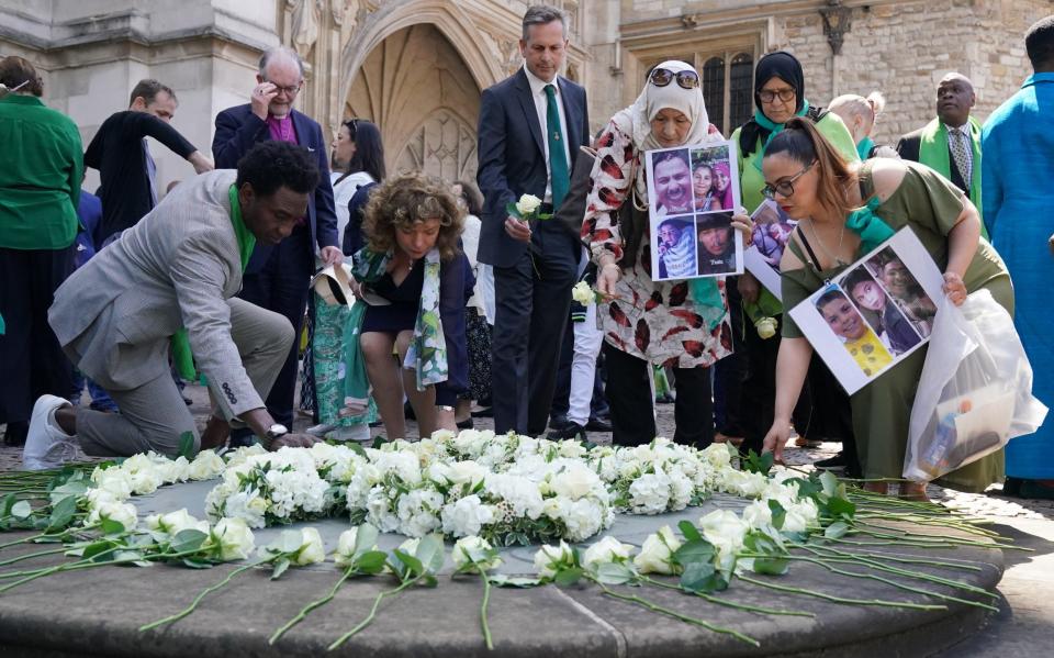 People carry photographs of lost loved ones as they lay flowers - WPA Pool/Getty Images Europe