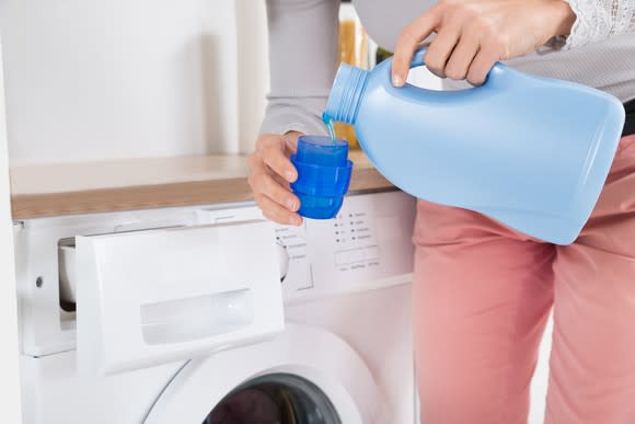 A woman measures out laundry detergent.