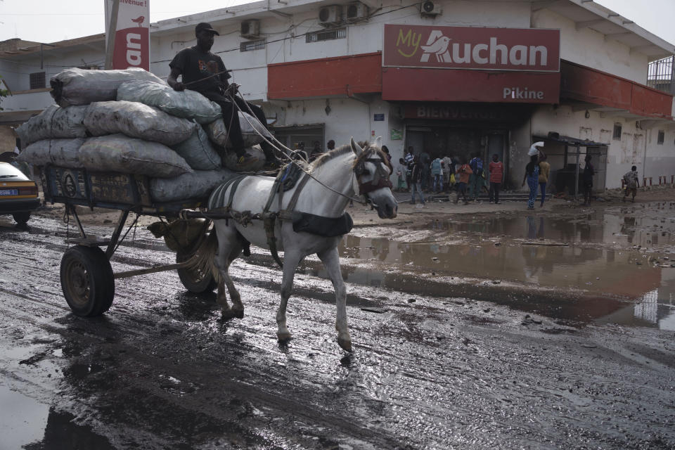 A man drives his horse-drawn cart past a supermarket that was damaged during protests yesterday in Pikine, Dakar region, Senegal, Tuesday, May 16, 2023. According to the authorities at least three people died, including a police officer who was hit by a police vehicle, in Dakar and Ziguinchor during clashes between security forces and supporters of Senegalese opposition leader Ousmane Sonko. (AP Photo/Leo Correa)