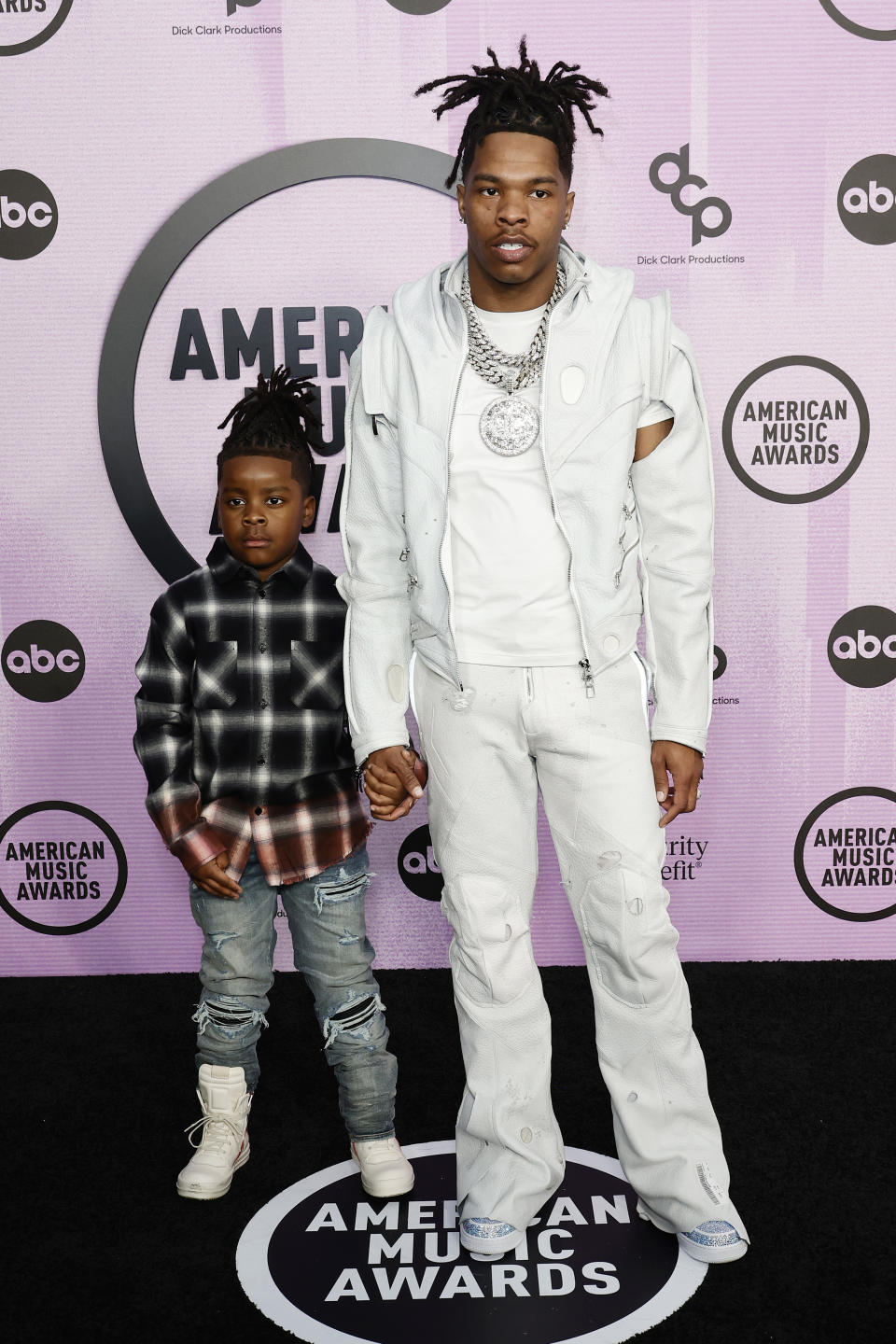 Lil Baby in white outfit with son on red for AMAs