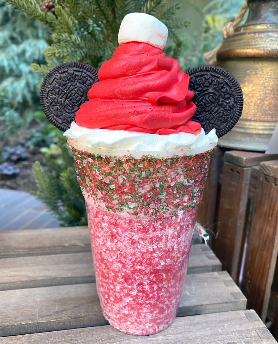 A large shake with red and green sprinkles, and whipped cream made to look like a santa hat and oreo cookies as the mickey ears