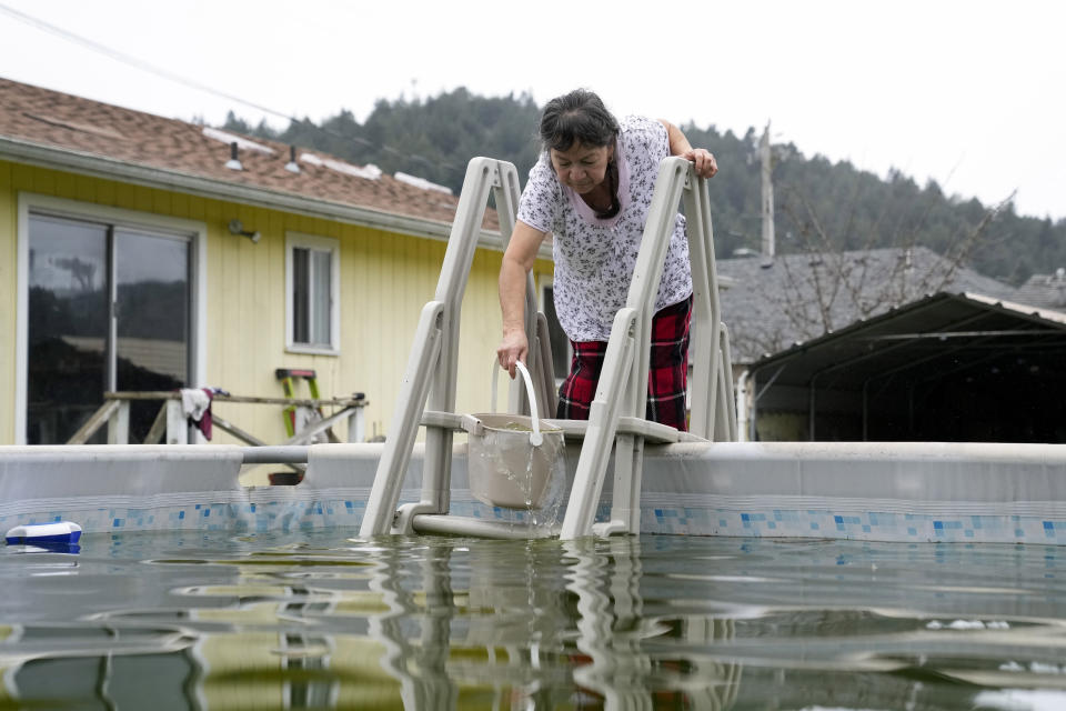 Celia Magdaleno, 67, collects water from her neighbor's pool to use for her toilet since water service has yet to resume following an earthquake in Rio Dell, Calif., Wednesday, Dec. 21, 2022. (AP Photo/Godofredo A. Vásquez)
